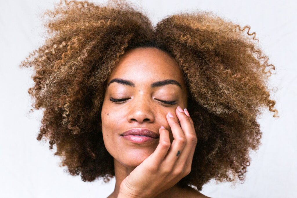 women with afro touching her face and looking down