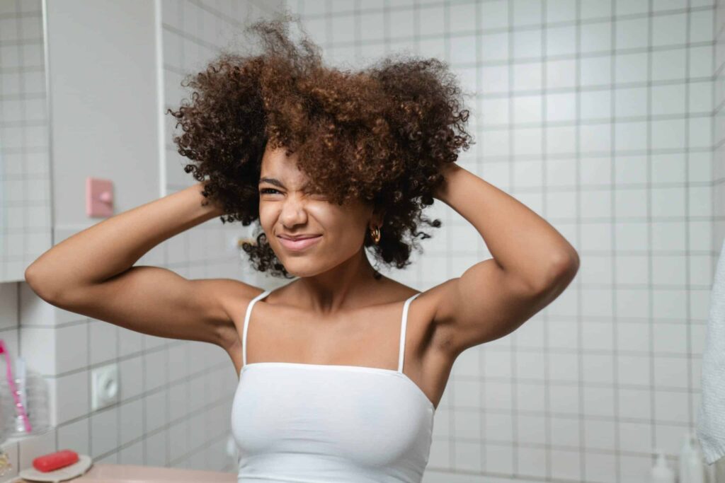 woman looking in the mirror with her hands in her hair