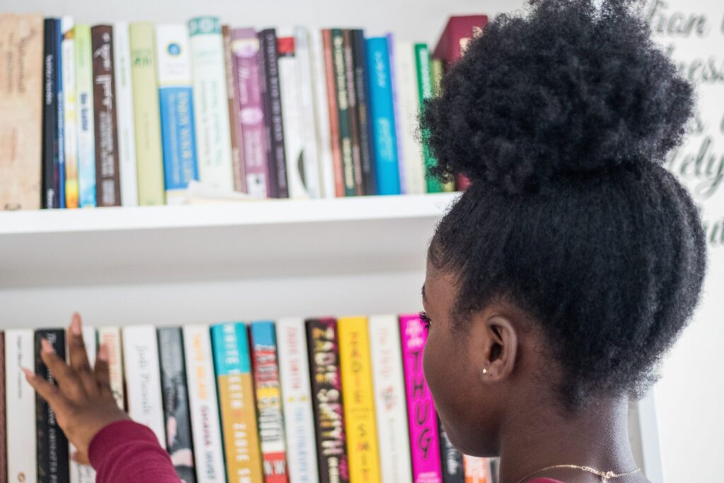 little girl looking at books on a shelf